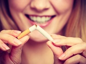 Smiling woman breaks down cigarette