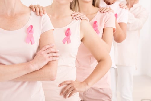 Caucasian women with pink ribbons holding hands on each other shoulders-img-blog